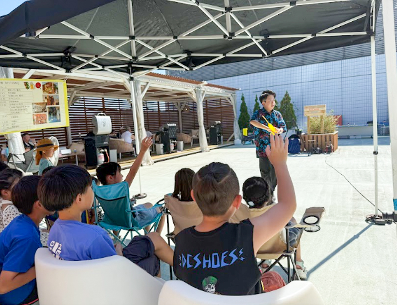 新横浜プリンスホテル屋上にてバルーンパフォーマンスを演じるCrystal Magician® Michelと手を上げる子どもたち