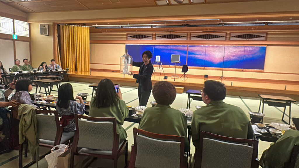 富士山温泉ホテル鐘山苑宴会場にてインドネシアからのゲストの目の前でボトルの中でハンカチが踊るマジックを披露するCrystal Magician® Michel