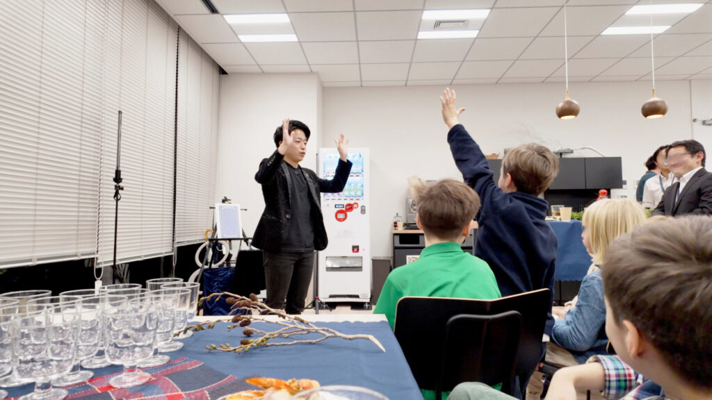 外資系ファンドのファミリーイベントにてマジックに参加してくれる子を探すCrystal Magician® Michelと手を上げる子ども