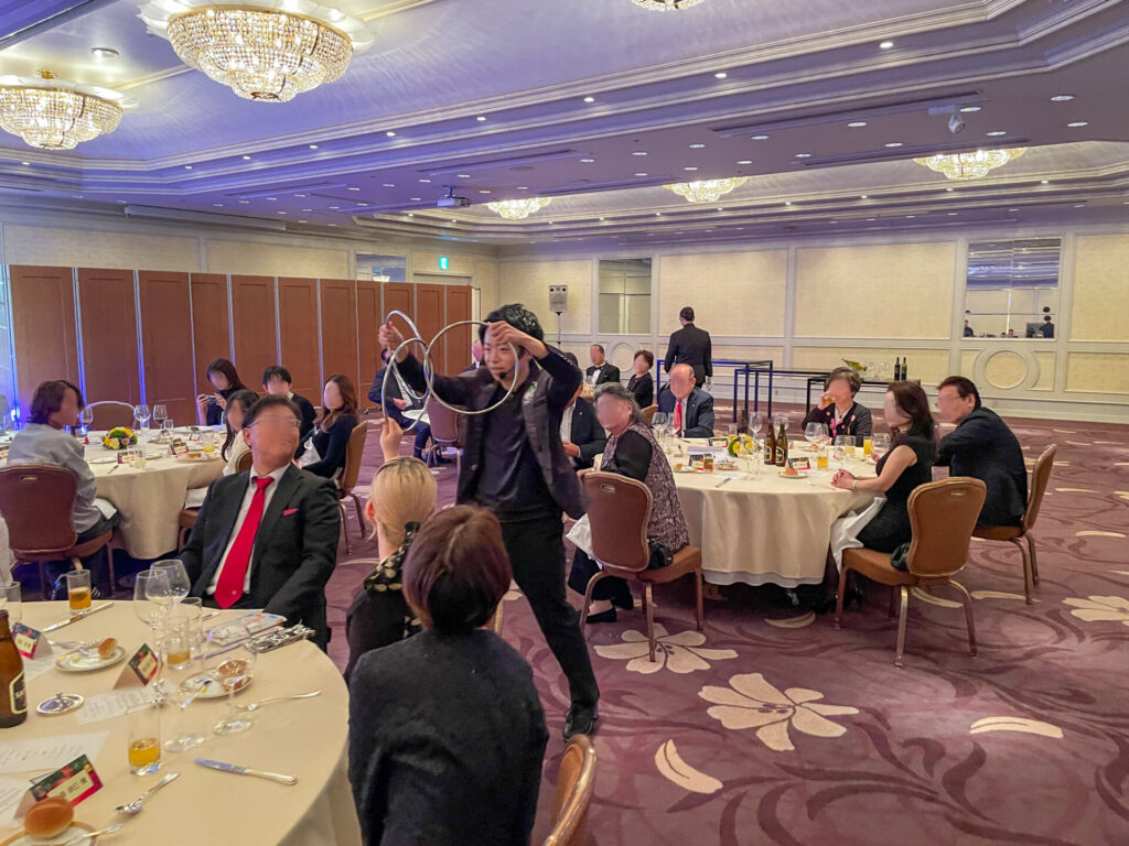 名古屋東急ホテル「雅の間」で千種ライオンズクラブの方々にリングマジックを演じるCrystal Magician® Michelとリングをつかんで参加するゲスト