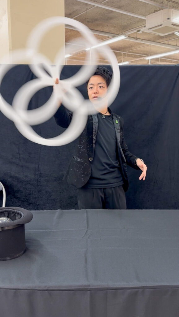 北海道北斗市のイオン上磯での携帯ショップイベントにて、白いリングを使った錯覚パフォーマンスを演じるCrystal Magician® Michel