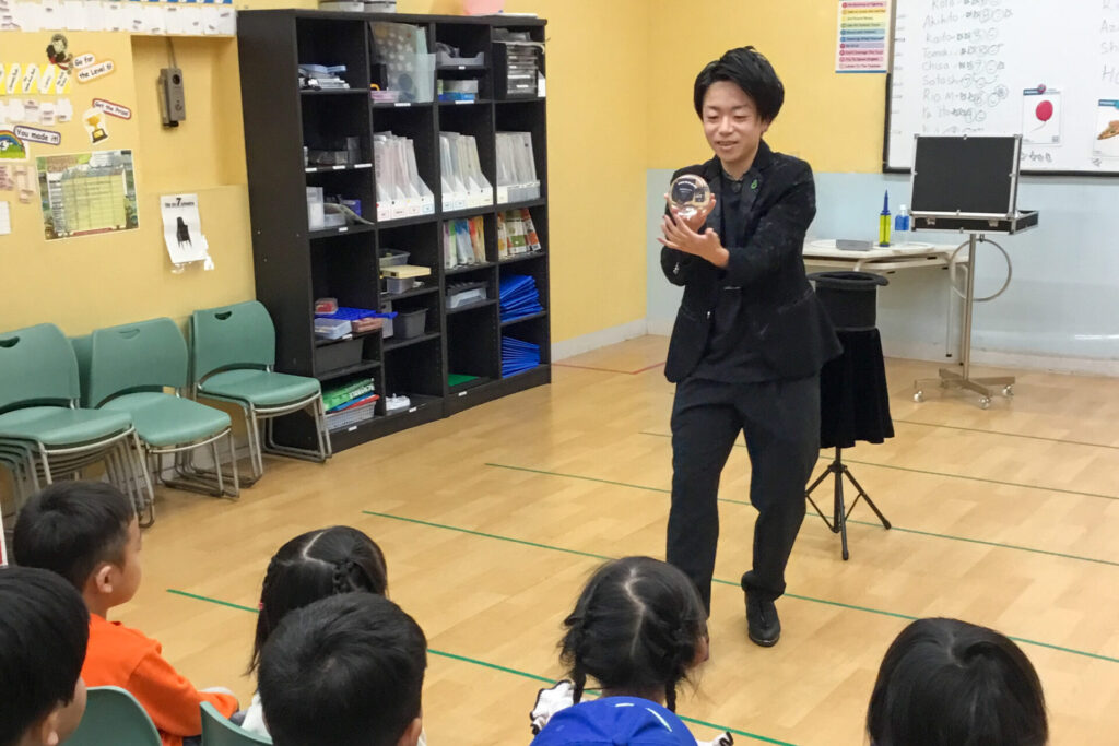 2026/1/5KidsDuo戸塚駅前のウィンタースクールイベントにて子どもたちの前で水晶玉を使ったコンタクトジャグリングを披露するCrystal Magician® Michel