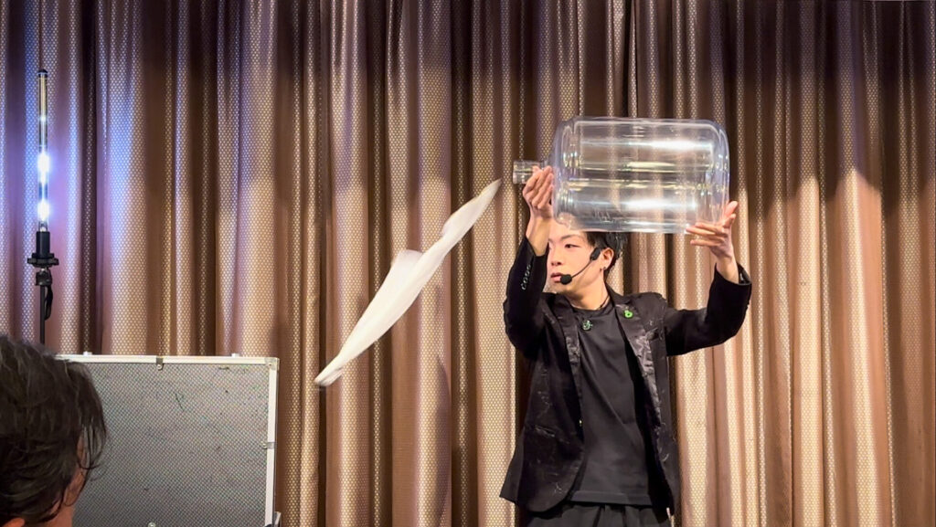 2026年2月2日、ザ・ウィングス海老名で開かれた海老名トラック地区会新年会にてCrystal Magician® Michelが演じたボトルの中をハンカチが自在に動くマジックの最後に、ハンカチが空中を飛びトランクに戻る様子